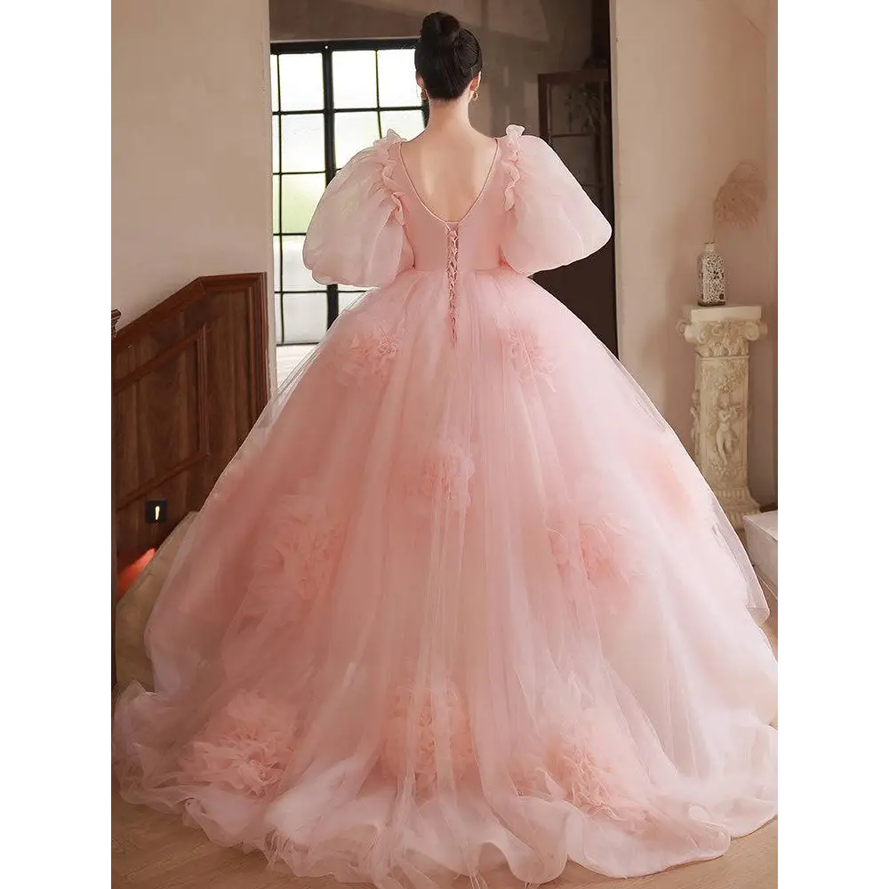 A soft blush pink high end banquet style host floral tulle gown with puffy sleeves and layered floral appliqué skirt