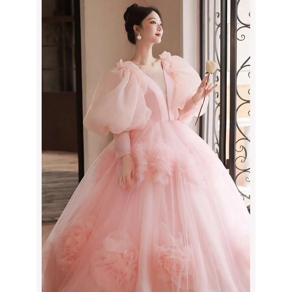 A soft pink high end banquet style host floral tulle gown with voluminous ball gown silhouette and puffy sleeves