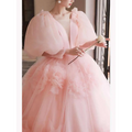 A soft pink tulle gown with voluminous puffed sleeves and floral appliqués designed for high end banquet style host events