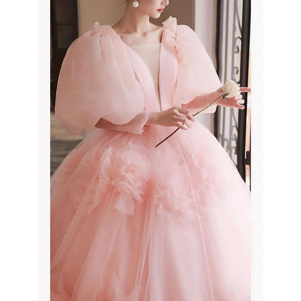 A soft pink tulle gown with voluminous puffed sleeves and floral appliqués designed for high end banquet style host events