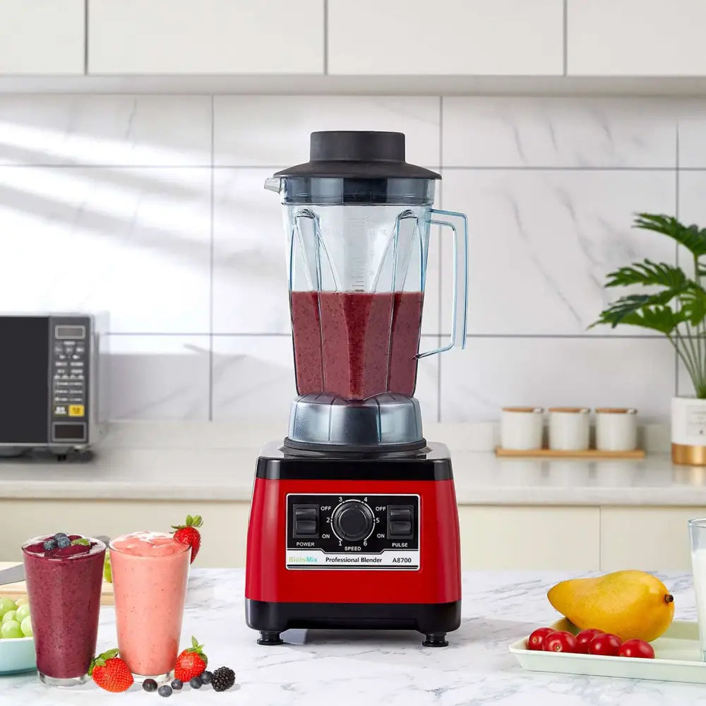 High-power commercial blender royale essence lux in red and black with clear glass pitcher filled with dark red smoothie
