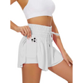 White high waist flowy athletic shorts with elastic waistband drawstring and side pockets holding a smartphone