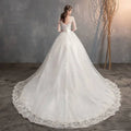 A flowing white high waist lace wedding dress with delicate lace detailing and a voluminous trailing skirt