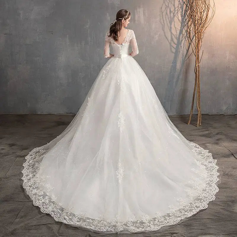 A flowing white high waist lace wedding dress with delicate lace detailing and a voluminous trailing skirt