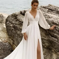 A flowing white wedding dress with long sleeve backless design and a high slit detail for elegant occasions