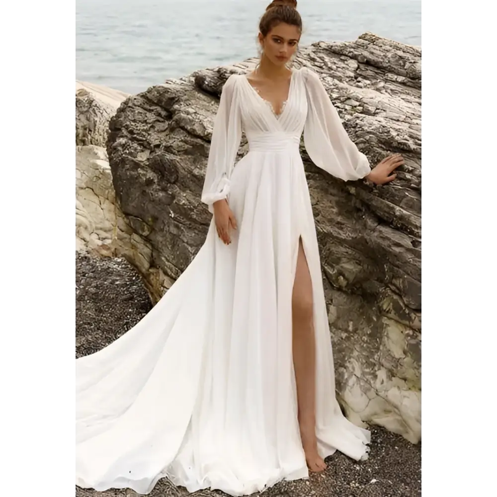 A flowing white long sleeve backless wedding dress with high slit and sheer sleeves for elegant bridal wear