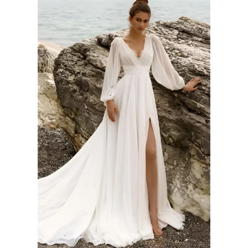 A flowing white long sleeve backless wedding dress with high slit and sheer sleeves for elegant bridal wear