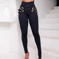 Black high waist skinny pants with a bold cross-belted metallic belt design and gold-toned metal buckles