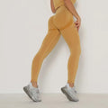 A pair of mustard-yellow high waist peach hip yoga pants with seamless ribbed fabric for comfortable wear
