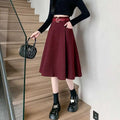 A flared burgundy woolen umbrella skirt with matching belt and brown high waist worn with black knit top and platform shoes