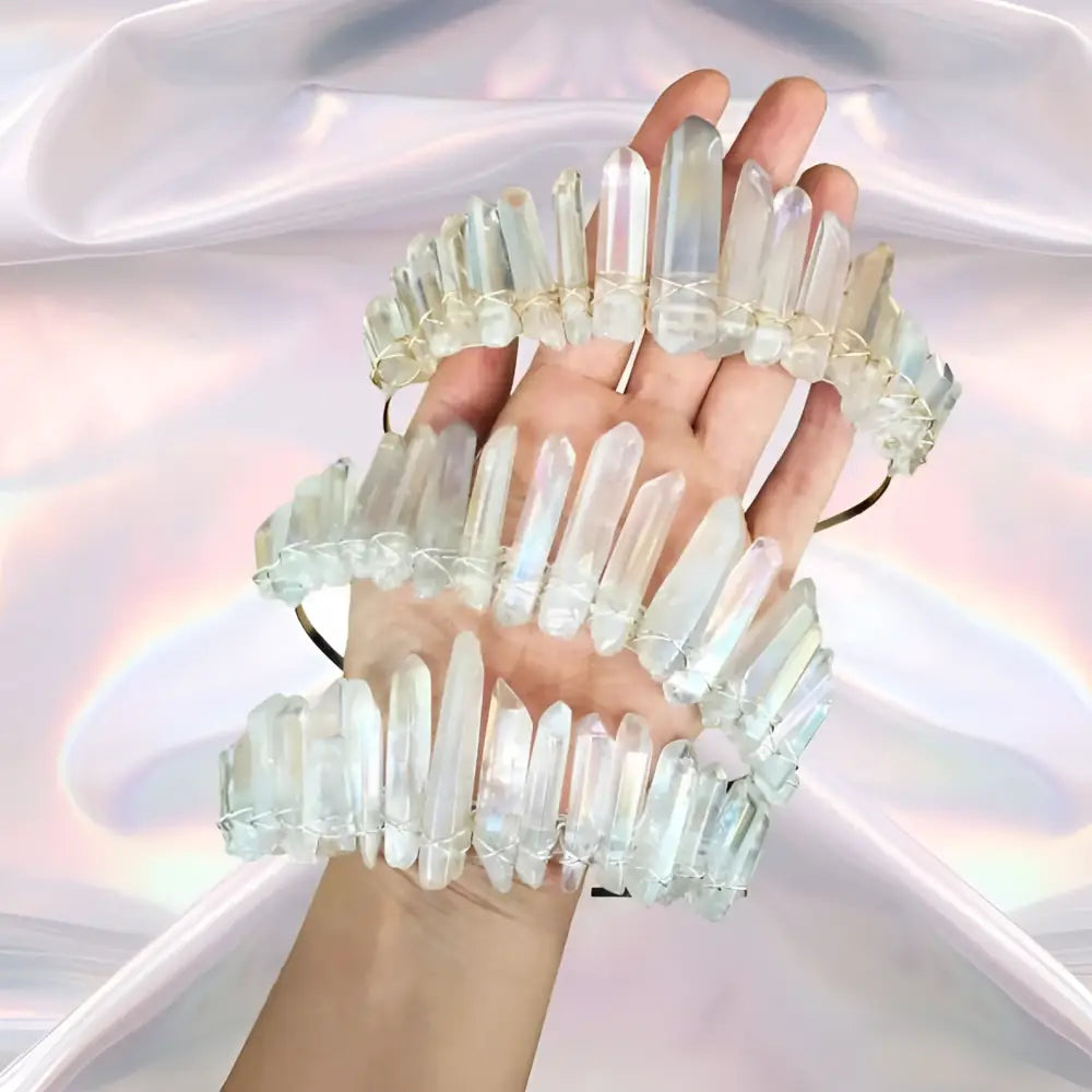 A hand holds three stacked iridescent quartz crown headbands with translucent white quartz and delicate wire bindings