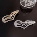 Two sweet cool rhinestone irregular lines bang hair clips in gold-tone and silver-tone on a dark surface
