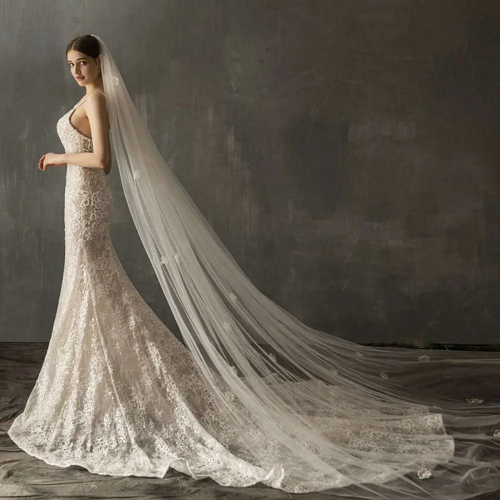 A flowing ivory lace bridal church wedding veil with delicate floral embroidery and a sheer layered pearl long tail design