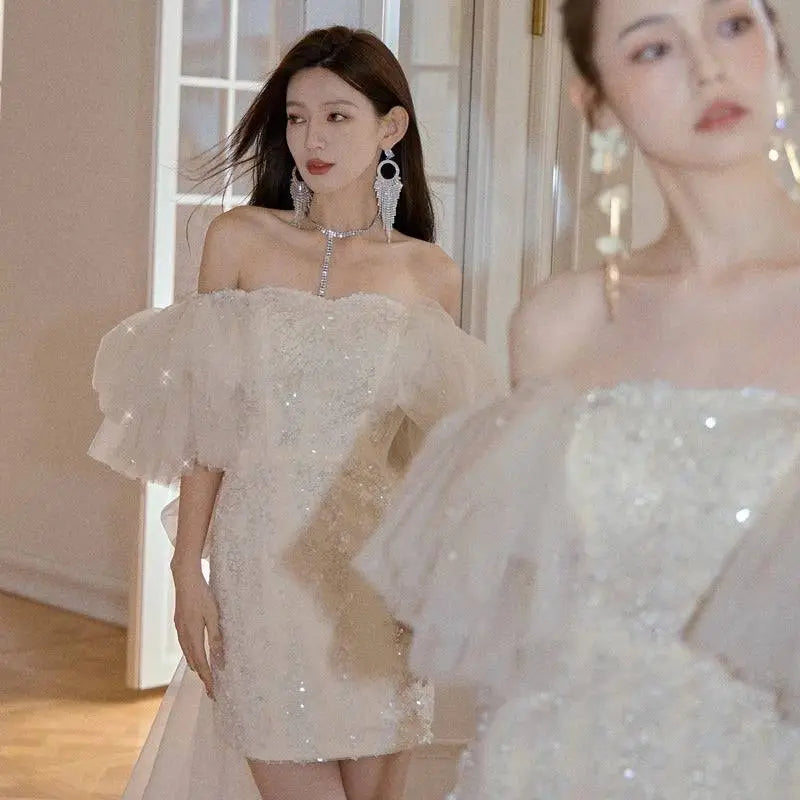 A shimmering ivory lace cinched waist miniskirt fairy dress featuring an off-the-shoulder design with delicate sequins