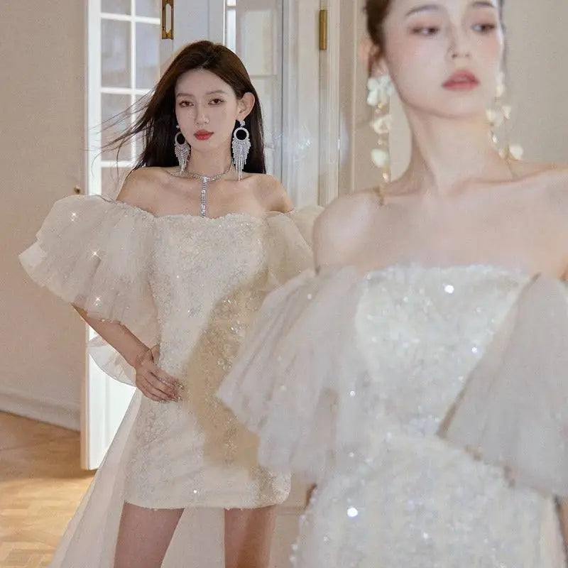 A shimmering ivory lace cinched waist miniskirt fairy dress featuring an off-the-shoulder design with delicate sequins