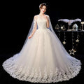 Elegant ivory lace wedding dress with intricate floral embroidery and sheer capelet featuring a flowing tulle skirt
