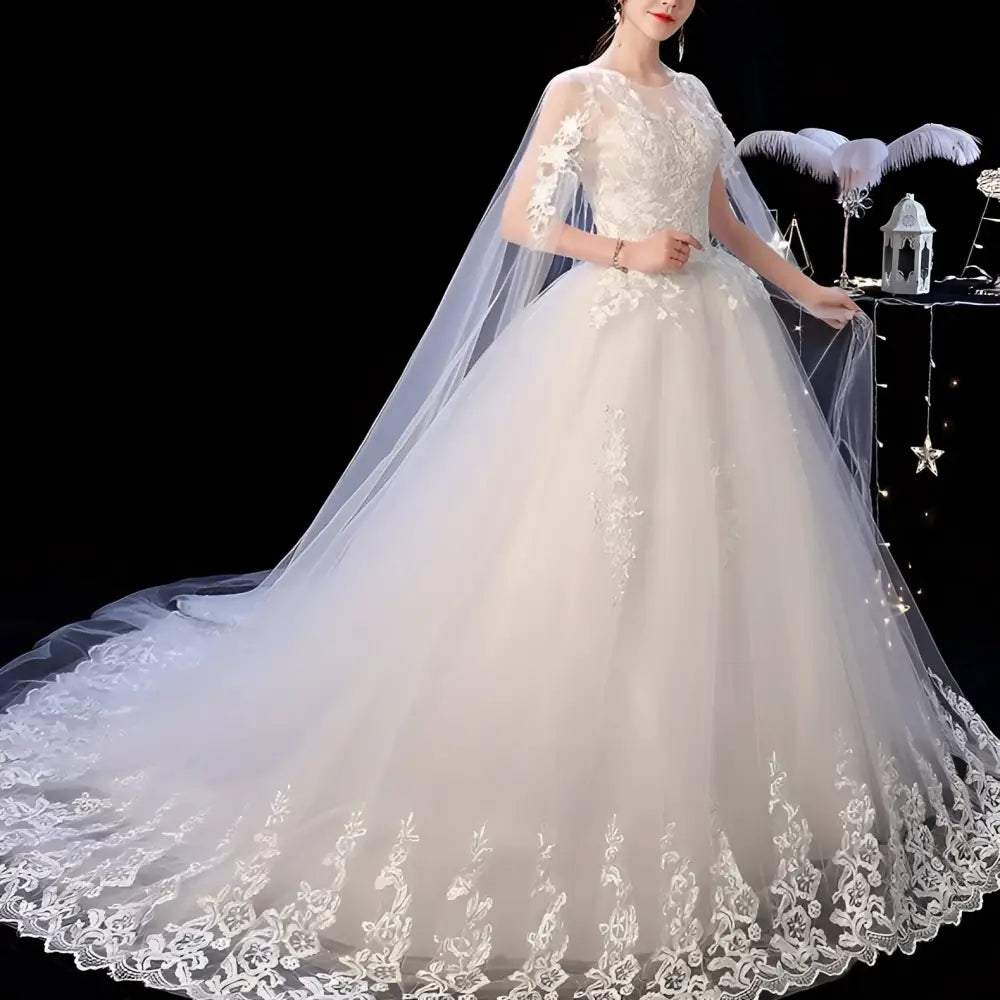 A flowing elegant ivory wedding lace dress with intricate white lace detailing and a sheer capelet