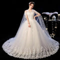 An elegant ivory wedding lace dress with intricate detailing and a sheer capelet for a sophisticated bridal look
