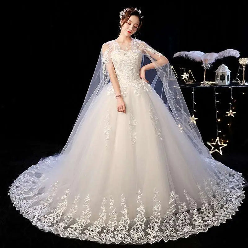 An elegant ivory wedding lace dress with intricate detailing and a sheer capelet for a sophisticated bridal look