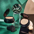 Black circular foundation compact with green white marbled lid moisture cushion containing beige air cushion foundation