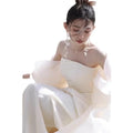 A flowing off-the-shoulder ivory satin outdoor travel shooting light yarn gown with airy fabric and ruffled sleeves