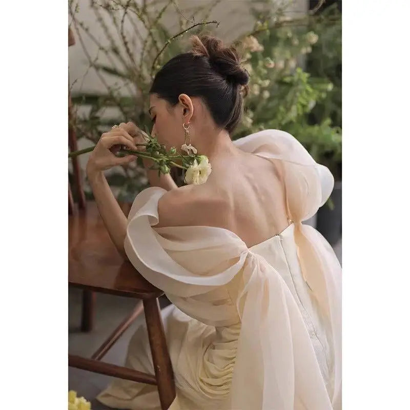 Ivory satin outdoor light yarn gown with delicate off-white fabric voluminous sheer puff sleeves and backless design