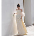 A flowing off-the-shoulder ivory satin outdoor travel shooting light yarn gown with voluminous sheer puff sleeves and draped bodice