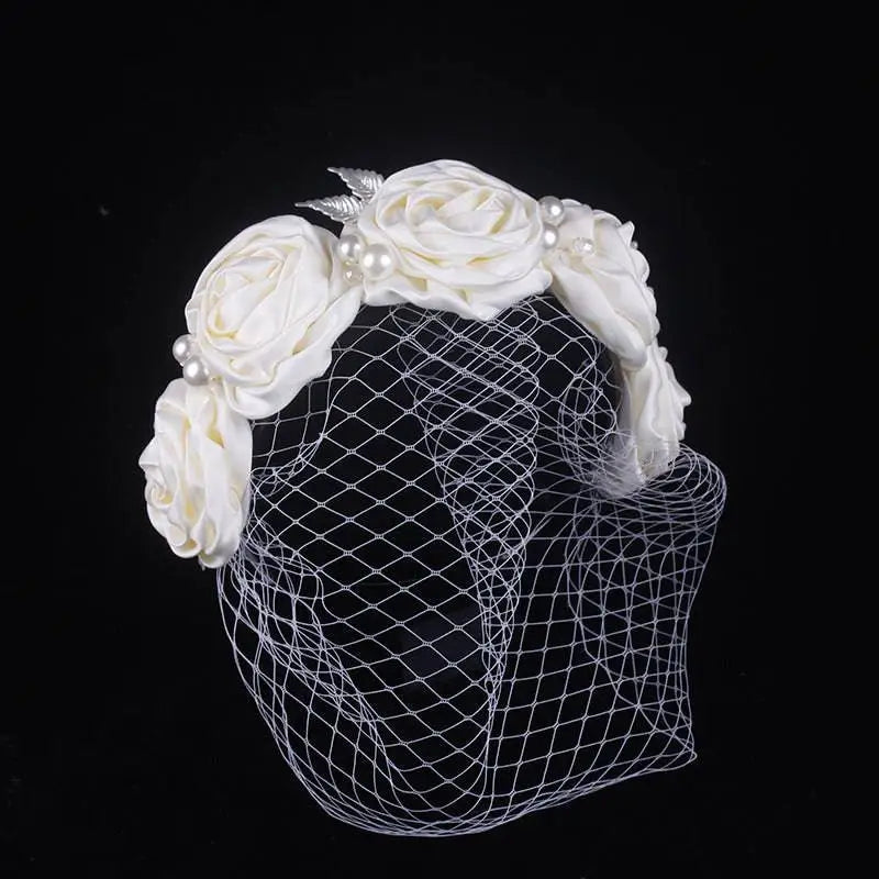 Ivory satin rose hair hoop headdress adorned with pearls and a delicate mesh veil for wedding dress styling
