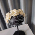 Elegant ivory satin rose hair hoop headdress adorned with delicate pearls and a sheer black veil for weddings