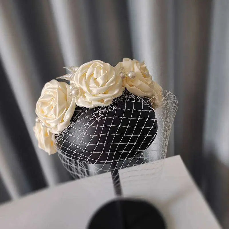 Elegant ivory satin rose hair hoop headdress adorned with delicate pearls and a sheer black veil for weddings