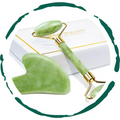Green jade facial roller and matching gua sha massage tool with gold-toned accents in a jade rolling and sha gift set