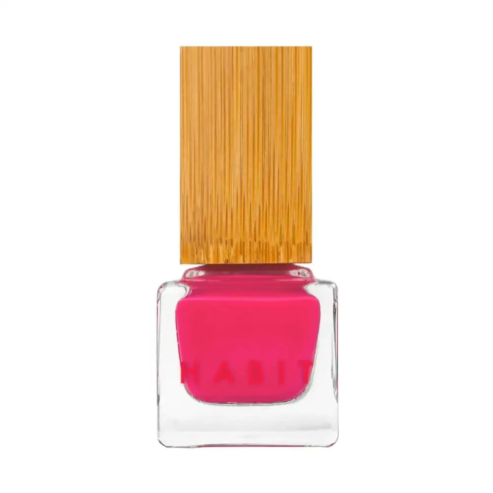 A vibrant kitten pink sustainably packaged nail polish in a clear glass bottle with a bamboo cap by Habit