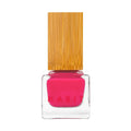 A vibrant fuchsia kitten pink sustainably packaged nail polish in a clear square glass bottle with a bamboo cap by habit
