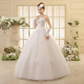 White lace wedding dress featuring a strapless bodice paired with a voluminous tulle skirt and long sheer gloves