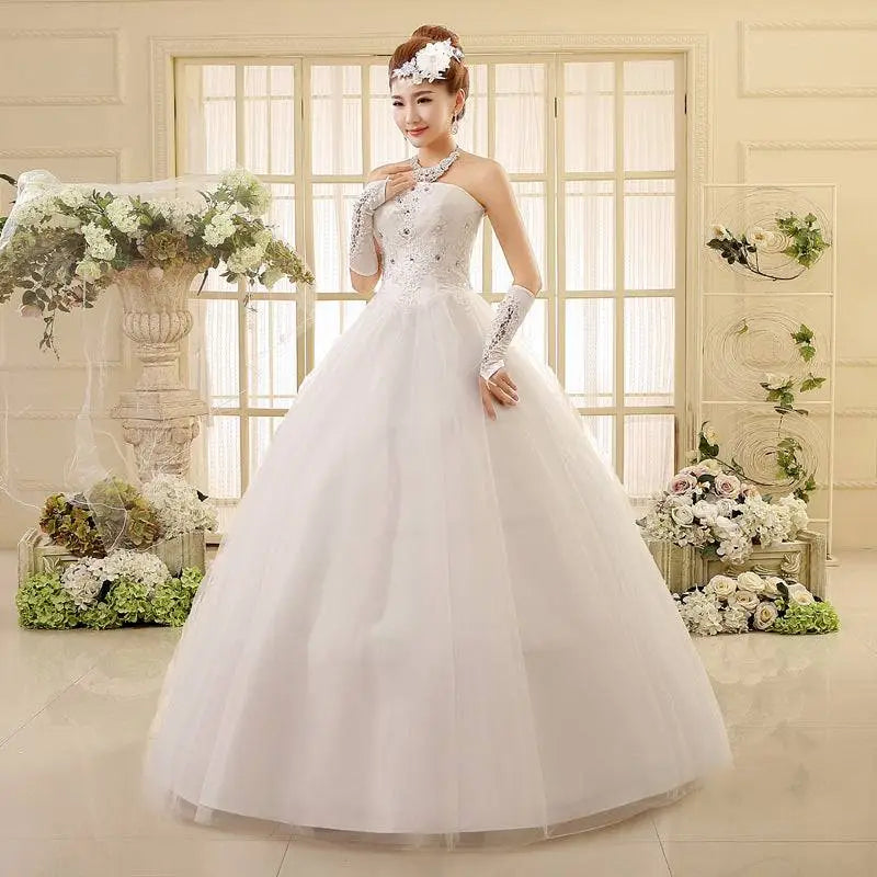 White lace wedding dress featuring a strapless bodice paired with a voluminous tulle skirt and long sheer gloves