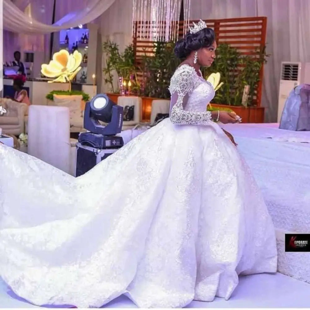White lace african wedding dress with long sleeves and an elaborate train ideal for african wedding ceremonies