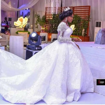 White lace african wedding dress with long sleeves and an elaborate train ideal for african wedding ceremonies