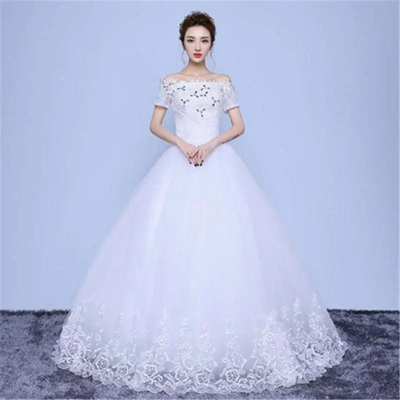 White off-the-shoulder wedding gown with intricate lace detailing and beaded floor length hemline in short sleeves