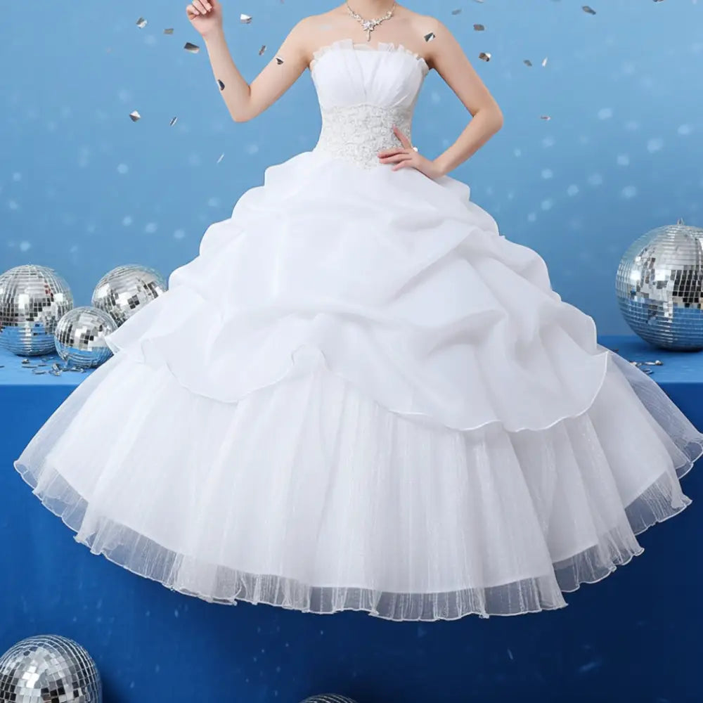 A white strapless beaded tulle bride wedding dress with a fitted bodice and layered tulle skirts for brides