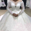 White lace ball gown wedding dress with long sheer sleeves and intricate floral pattern for elegant occasions