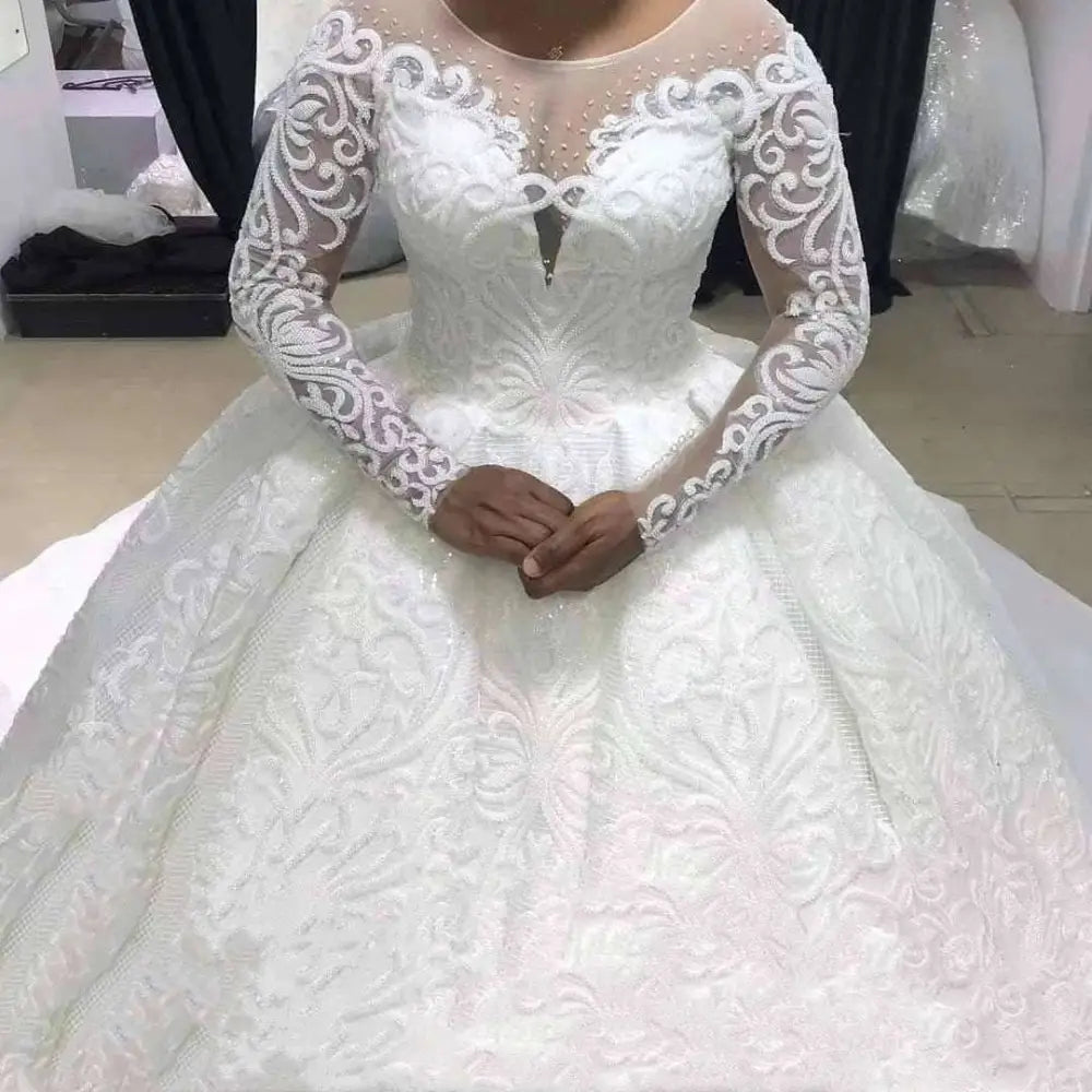 White lace ball gown wedding dress with long sheer sleeves and intricate floral pattern for elegant occasions