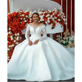 White lace ball gown wedding dress with long sheer lace sleeves and intricate beaded detailing on bodice and skirt