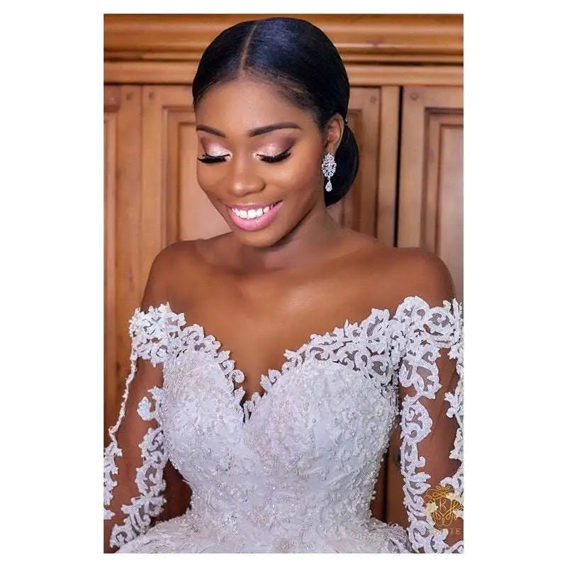 A white lace long sleeve custom wedding gown featuring intricate floral detailing and off-the-shoulder design
