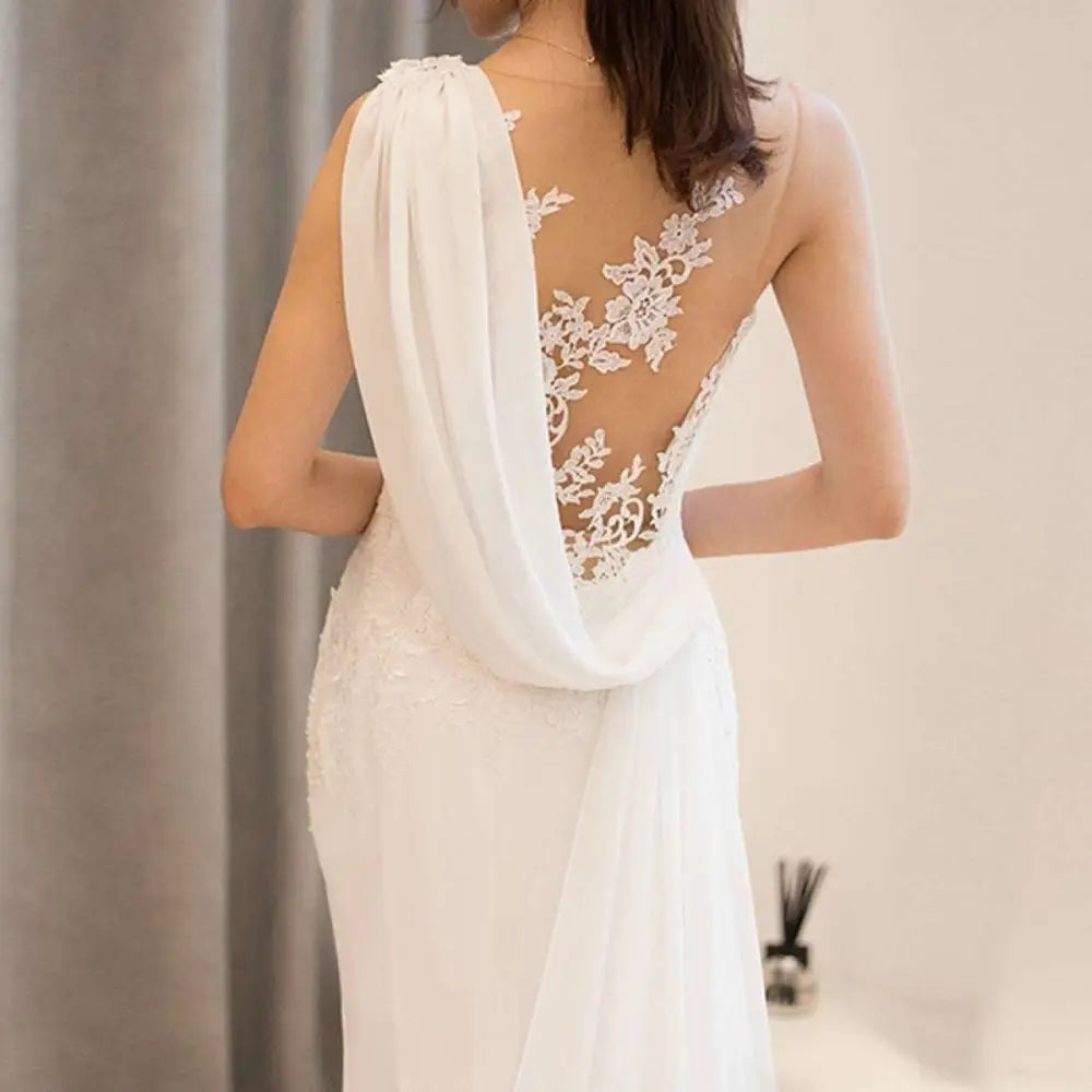 Back side of a white lace mermaid super fairy light wedding dress with intricate lace and sheer draped fabric panel