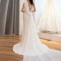 A flowing white lace mermaid super wedding dress with intricate lace detailing and sheer draped fabric on the back