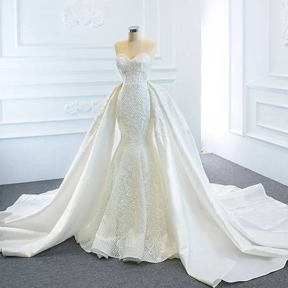 A white lace mermaid wedding dress with intricate detailing and two fishtail train flowing elegantly