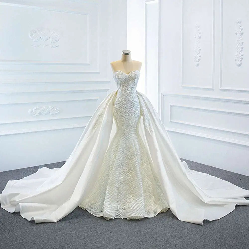 A white lace mermaid wedding dress with intricate detailing and two fishtail train flowing elegantly