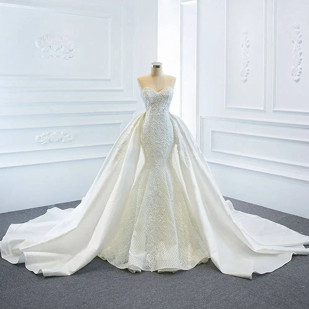 A stunning white lace mermaid wedding dress with intricate detailing and a flowing two fishtail train