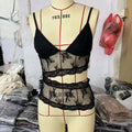 Black lace stitched backless small sling v neck tank top with sheer mesh panels and floral embroidery on mannequin