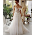 A flowing white wedding dress with lace strap backless design and intricate lace detailing with a deep v neckline